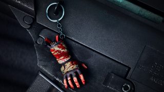 Eine blutverschmierte abgetrennte Hand mit einem Waffen-Talisman an einem Schlüsselring.