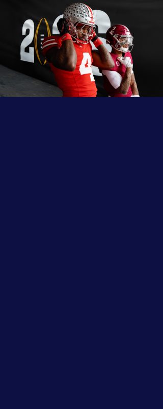 College Football athletes Ryan Williams from Alabama Crimson Tide and Jeremiah Smith from Ohio State posing in front of a big flag with all the other College Football teams