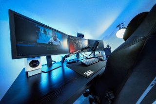 Modern gaming and streaming setup with triple monitors, microphone, keyboard, and accessories on a desk, with EA Sports branding visible on the microphone arm.