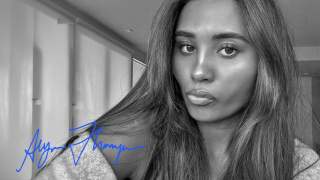 Black and white selfie picture of Alyssa Thompson with her signature on the bottom left. She is looking into camera, with her long hair falling over her shoulder.