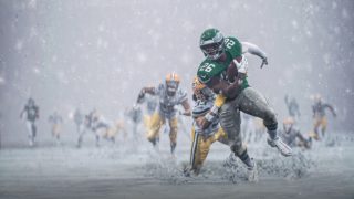 Football player in green uniform evades tackle on snow-covered field, focused on advancing the ball amidst heavy snowfall, with teammates and opponents in pursuit.